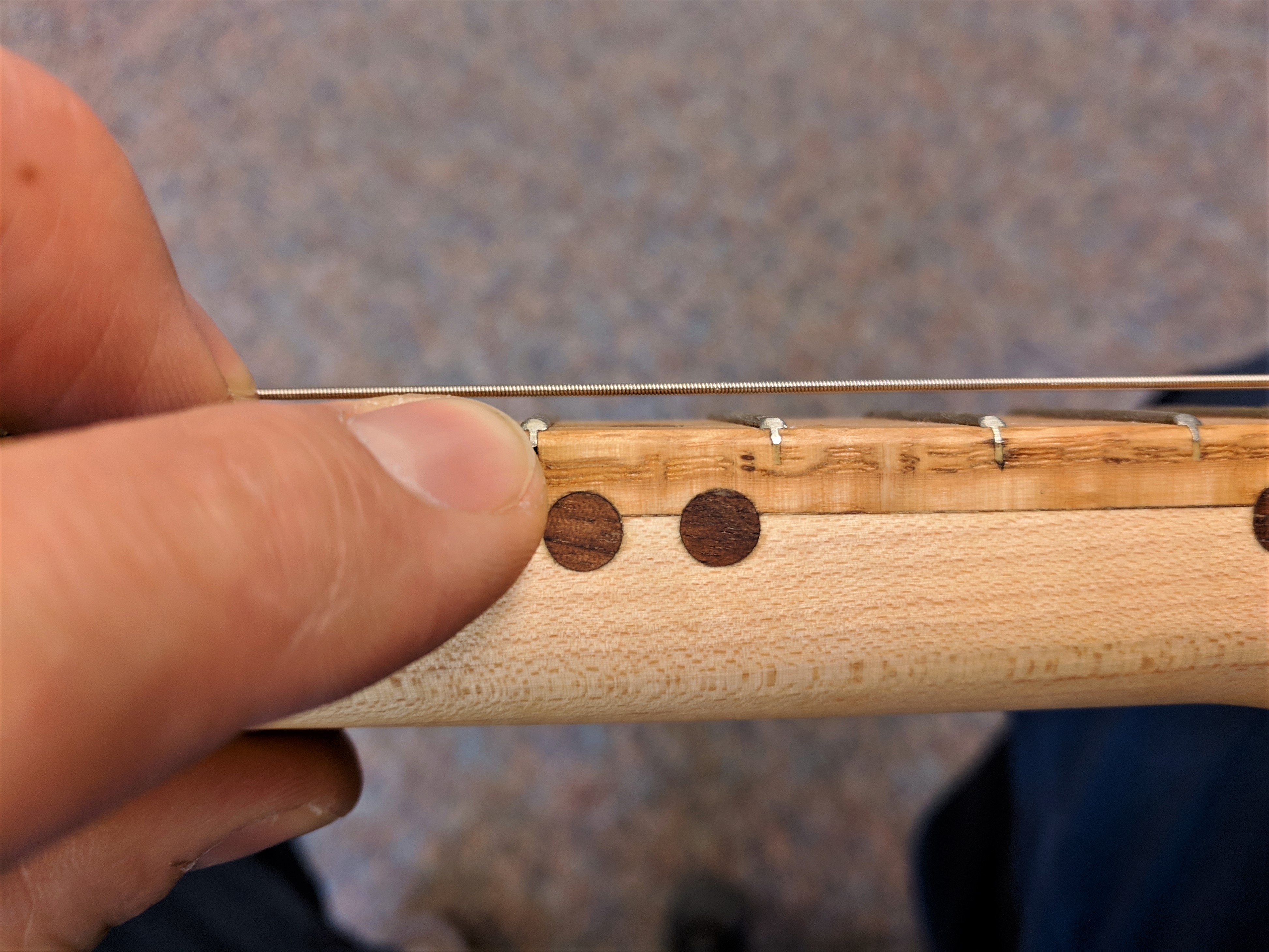 Finger pointing to action (string height) on a cigar box guitar