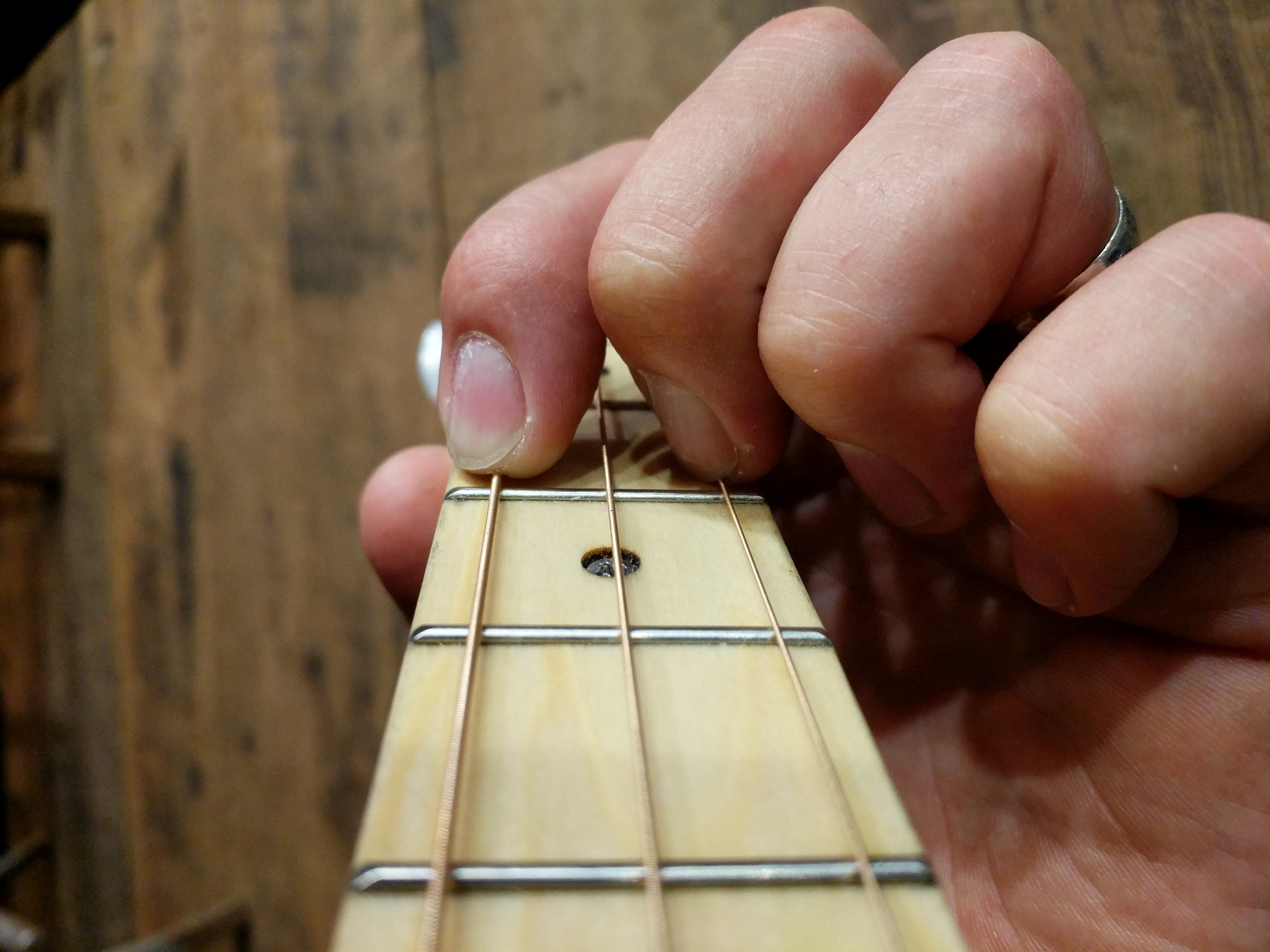 Arched fingers in D chord form on 3-string cigar box guitar tuned G-D-G