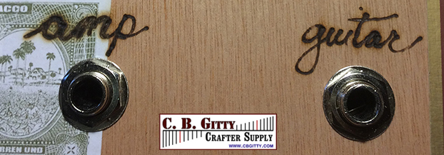 Input and output jacks for the C. B. Gitty Psycho Knob marked on the cigar box exterior