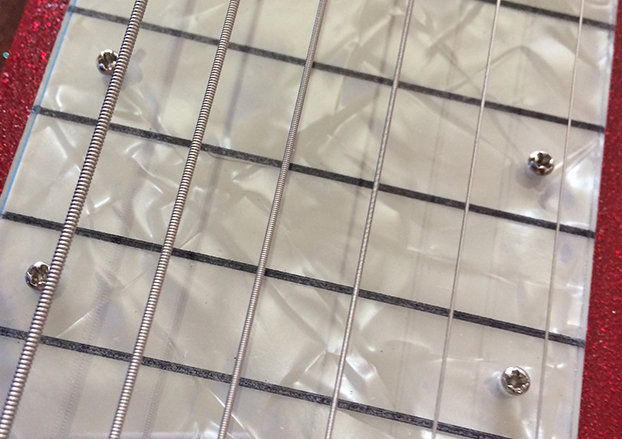 White pearl underlay beneath acrylic fretboard 