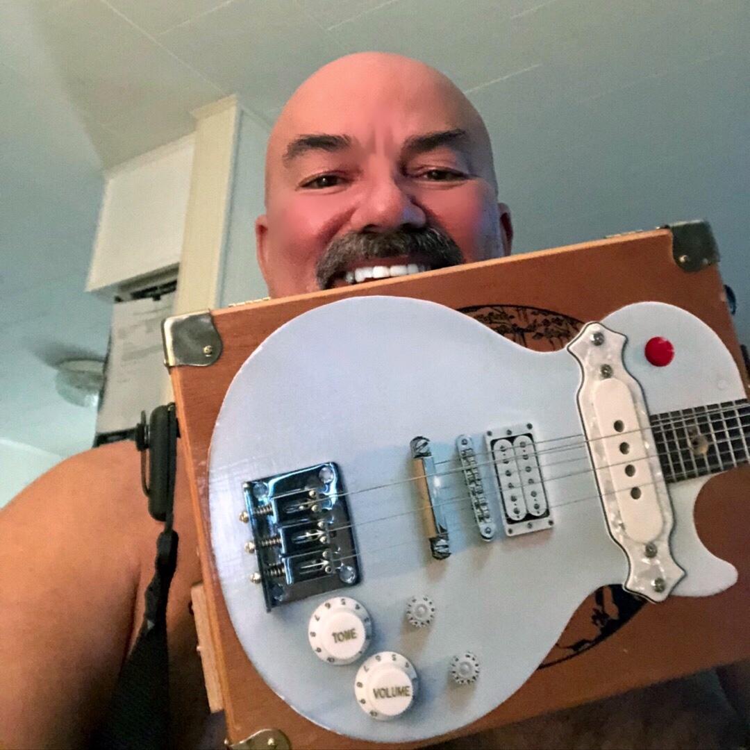Rick G. holding his Buckethead-tribute cigar box guitar