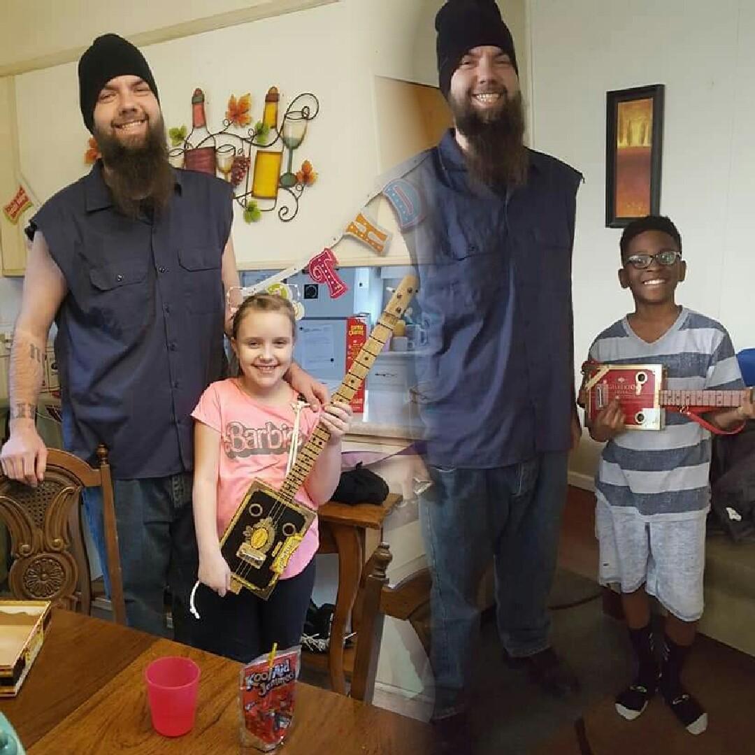 Steebos giving cigar box guitars to two children